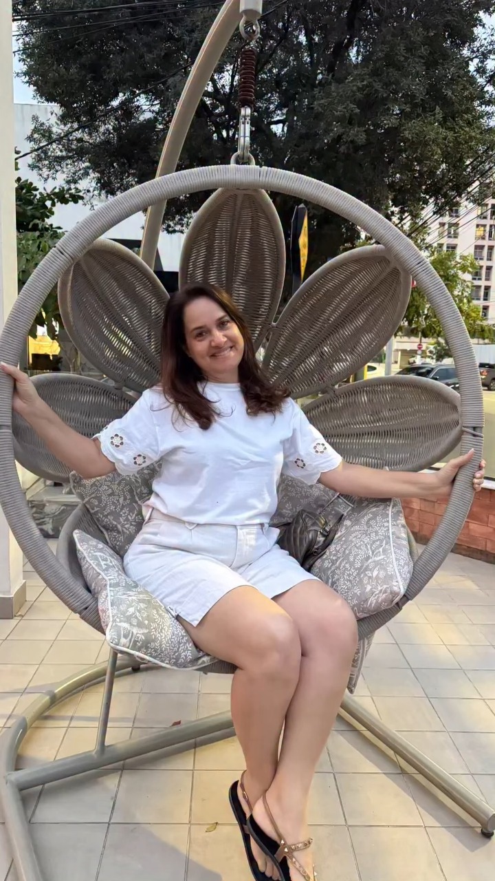 Jesiane sorrindo, sentada numa cadeira em forma de flor